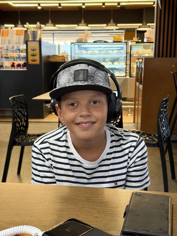 Thiago mit Cap und Kopfhörern im Café (Originalfoto)
